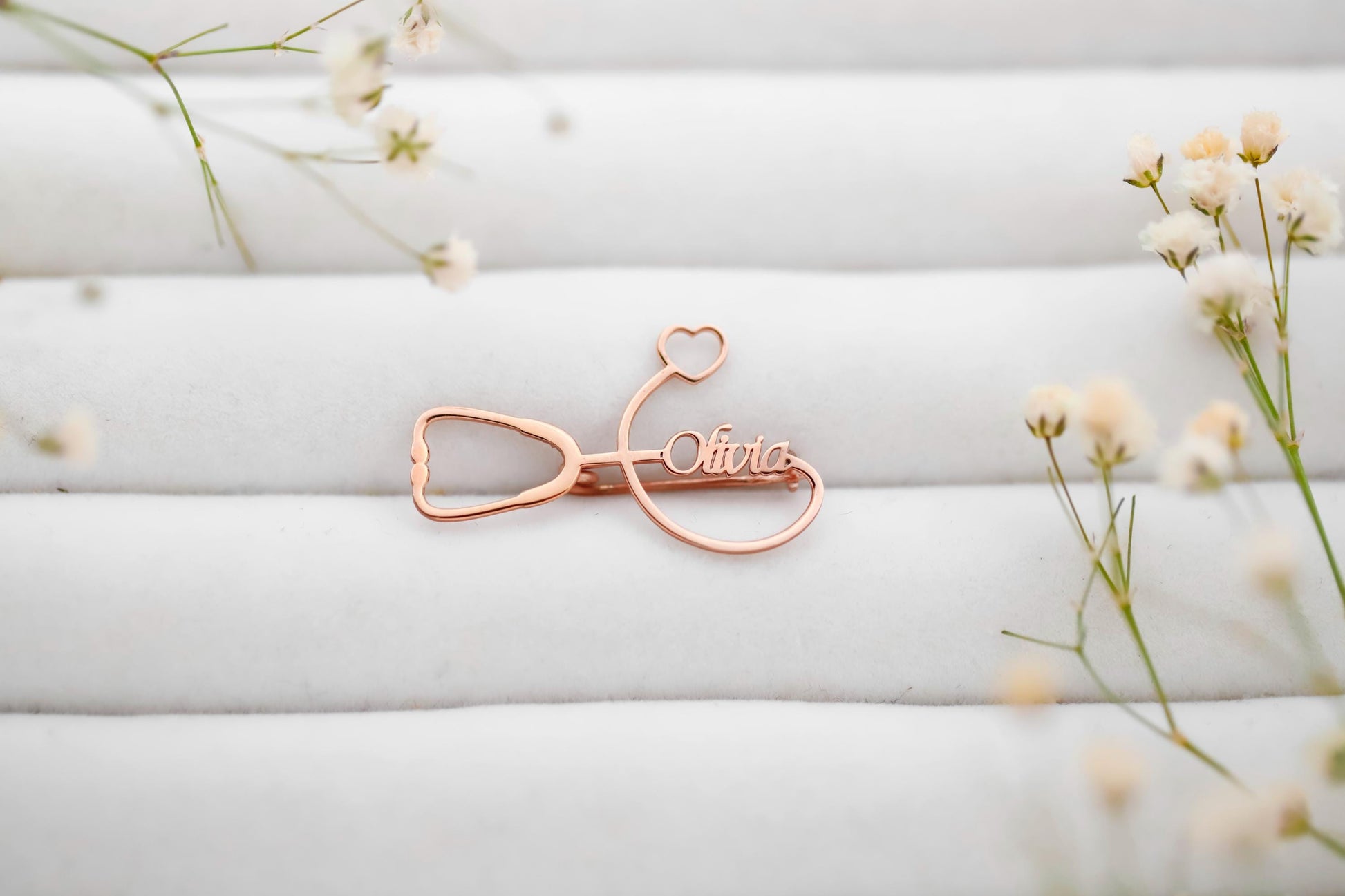 Rose gold name clip with 'Olivia' on a white background with delicate flowers