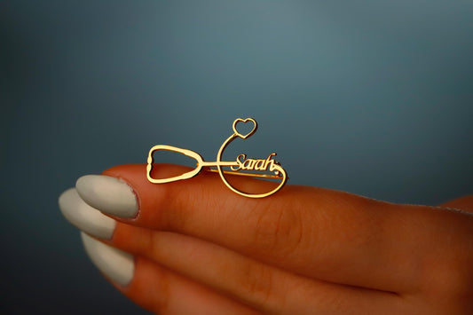 Gold necklace with 'Sarah' engraved on a hand against a dark background