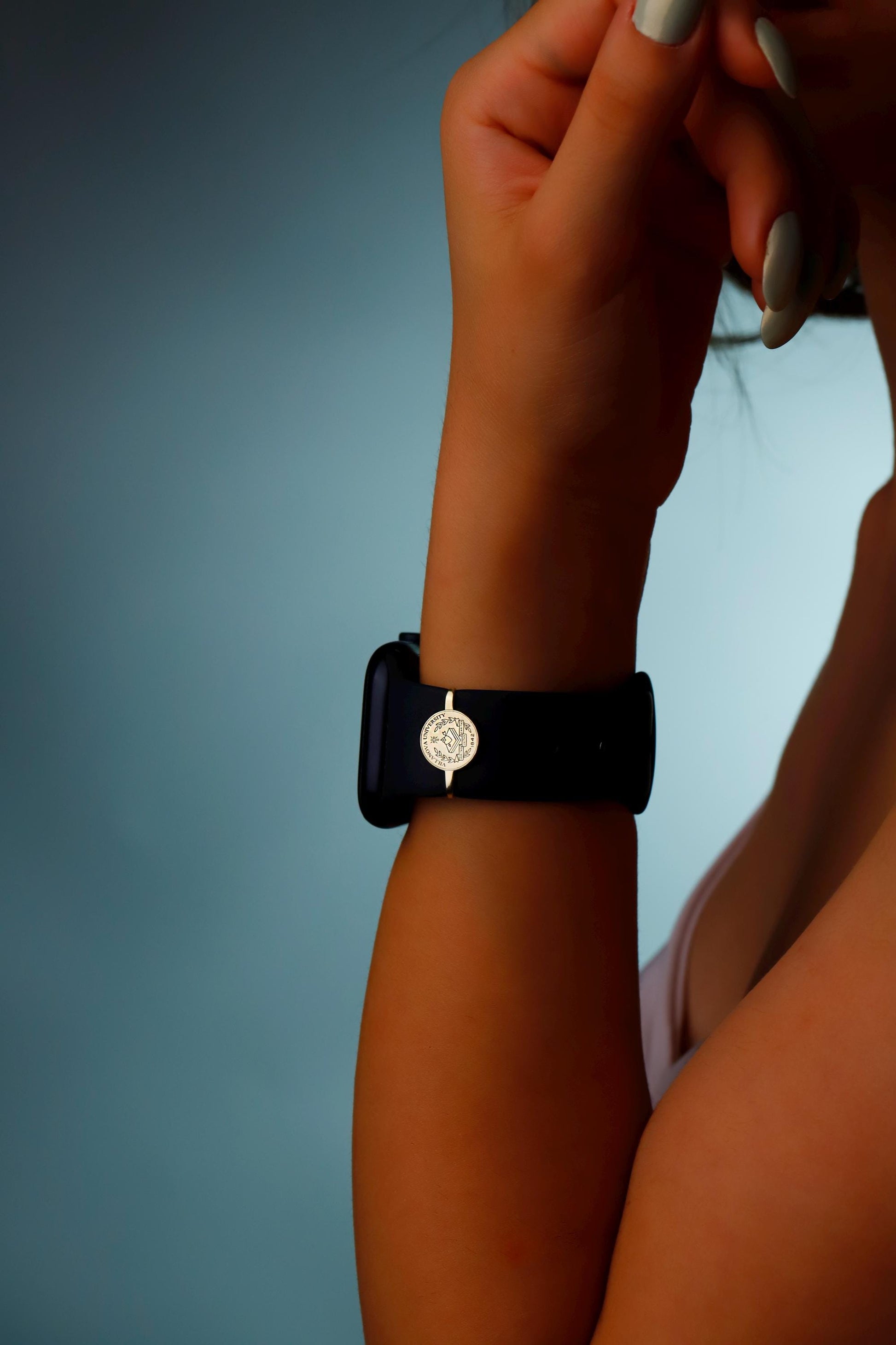 Hand wearing a black smartwatch with a blue background