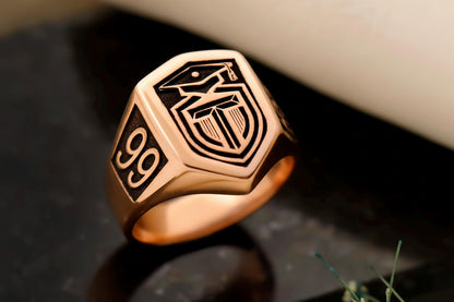 Rose gold ring with engraved design on a dark surface