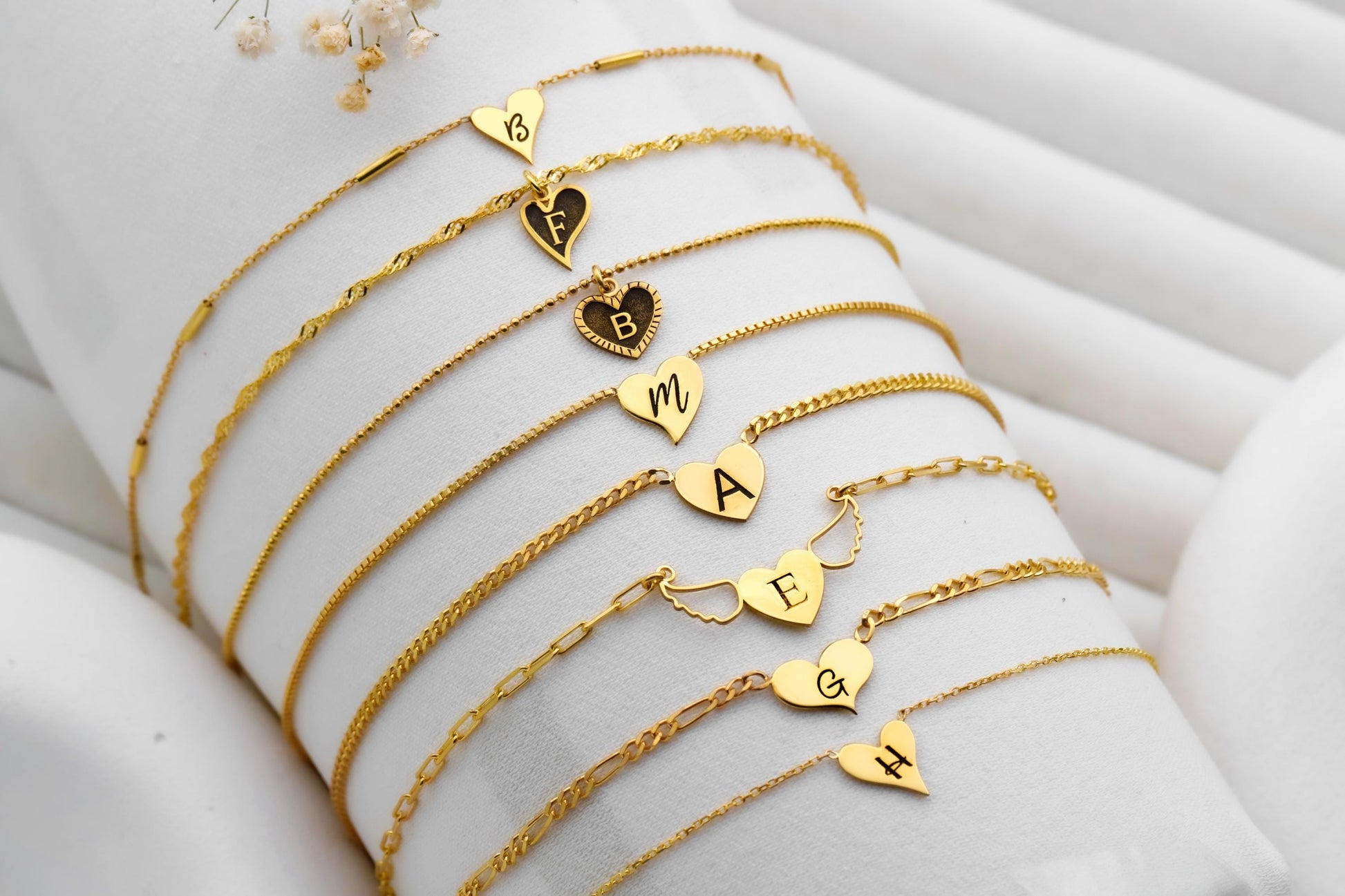Gold bracelets with heart-shaped charms on a white surface