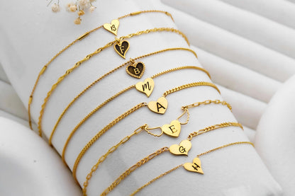 Gold bracelets with heart-shaped charms on a white surface