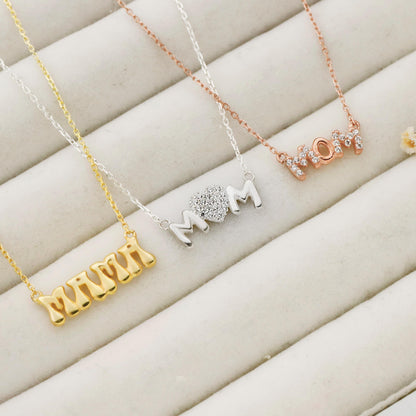 Four necklaces in gold, silver, and rose gold on a beige surface