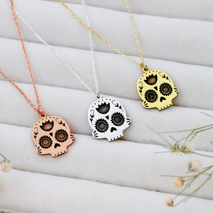 Three skull-shaped pendants on necklaces with rose gold, silver, and gold colors against a white background.