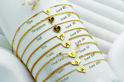 Gold bracelets with various charms and inscriptions on a white surface