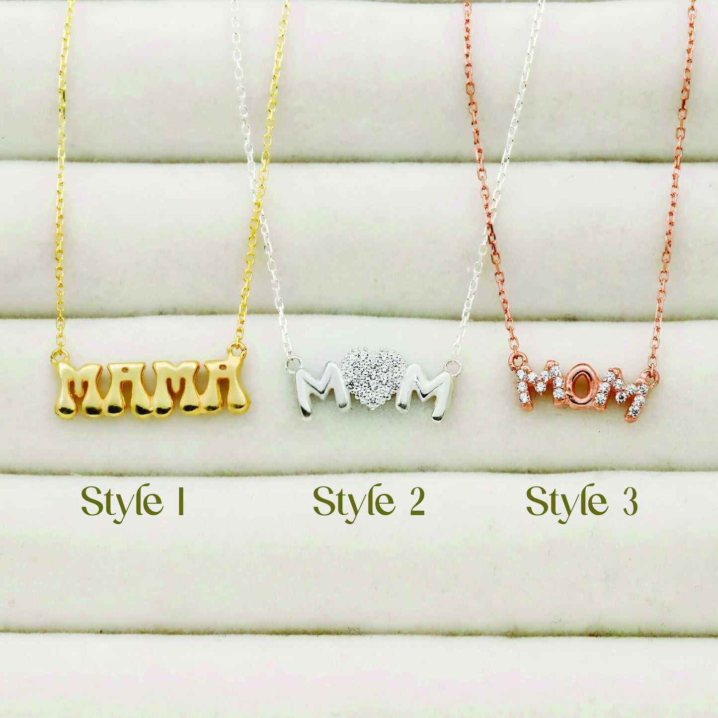 Three 'MOM' necklaces in different styles and colors on a white background