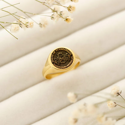 Gold ring with engraved design on a beige surface with small flowers