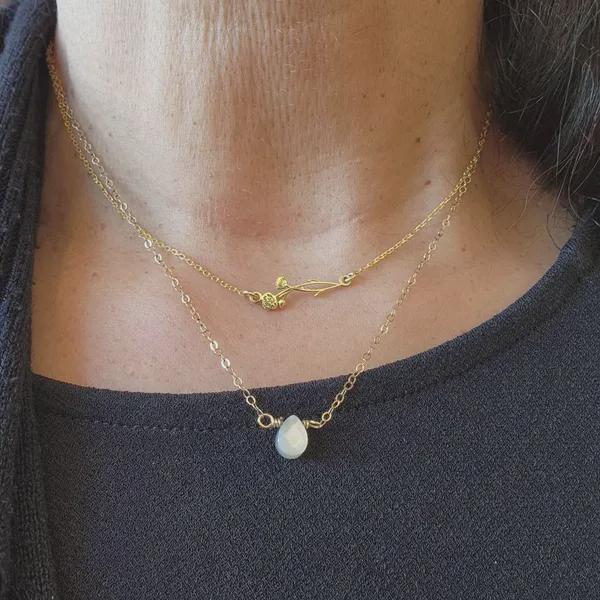 Close-up of a person wearing two gold necklaces with a dark background