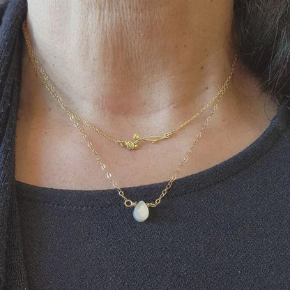 Close-up of a person wearing two gold necklaces with a dark background