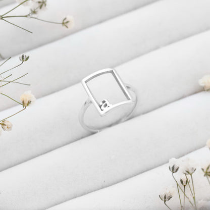 Silver ring with a diamond on a white fabric background with small flowers.