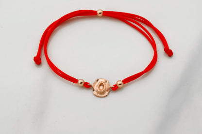 Red bracelet with gold beads on a light gray background