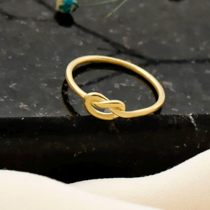 Gold knot ring on a dark stone surface