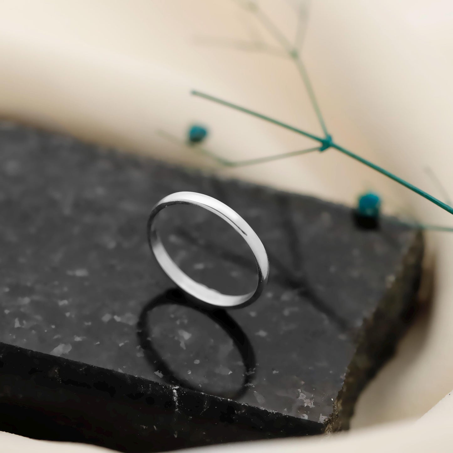 Silver ring on a black stone surface with a blurred background