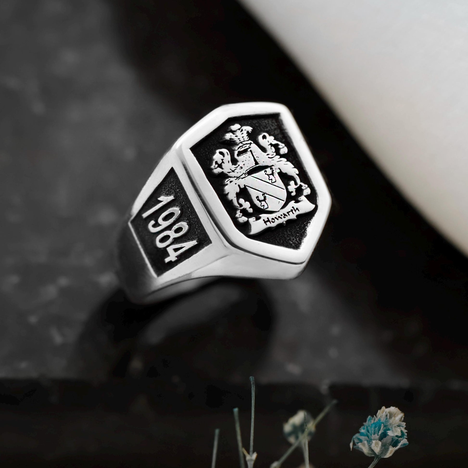 Silver ring with emblem and '1984' engraving on a dark background