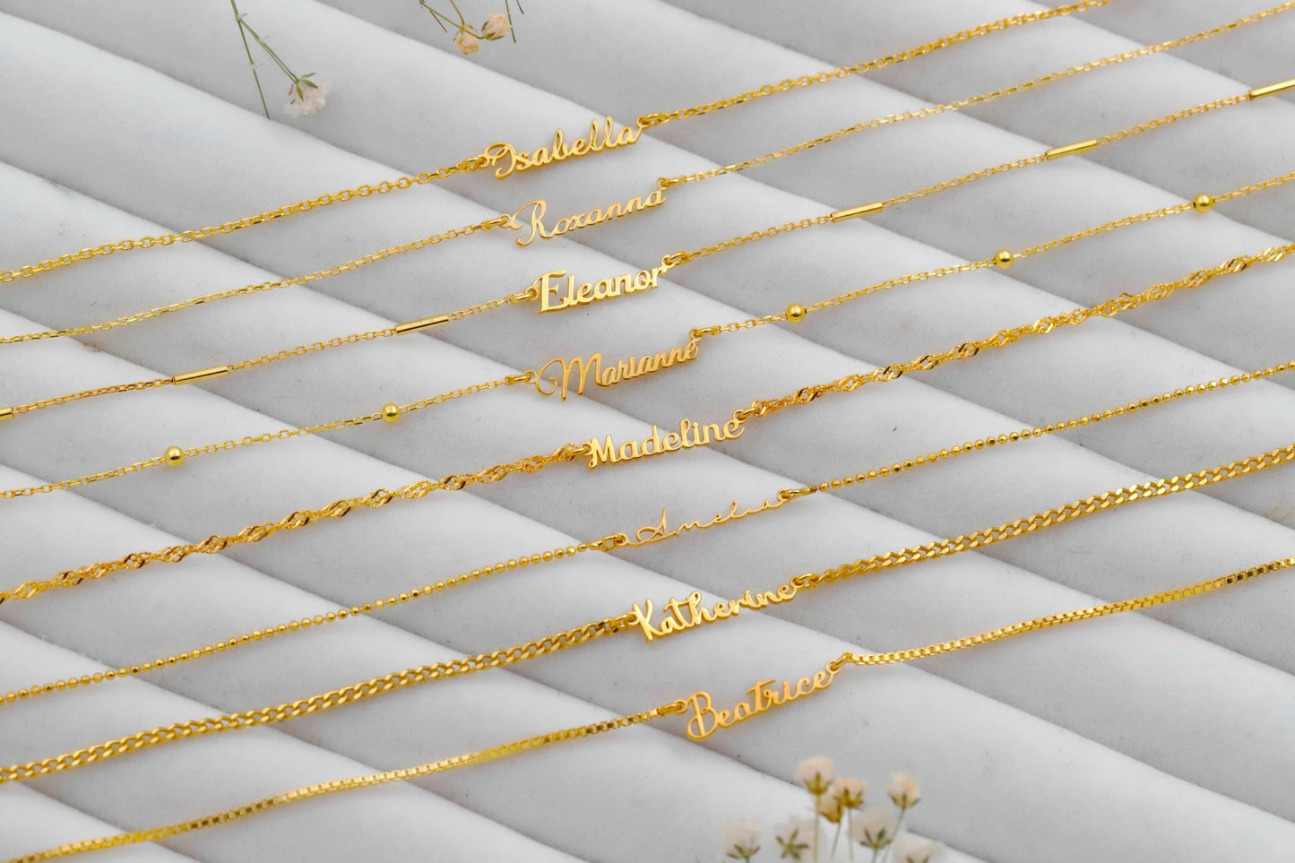 Gold name necklaces on a textured gray surface