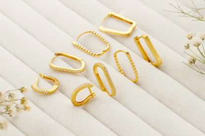 Set of gold hoop earrings on a white surface with small flowers.