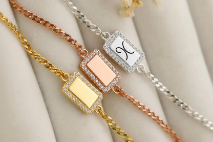 Three gold, rose gold, and silver bracelets with engraved symbols on a beige surface.