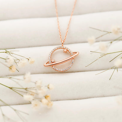 Rose gold necklace with a heart-shaped pendant on a white surface with delicate flowers.