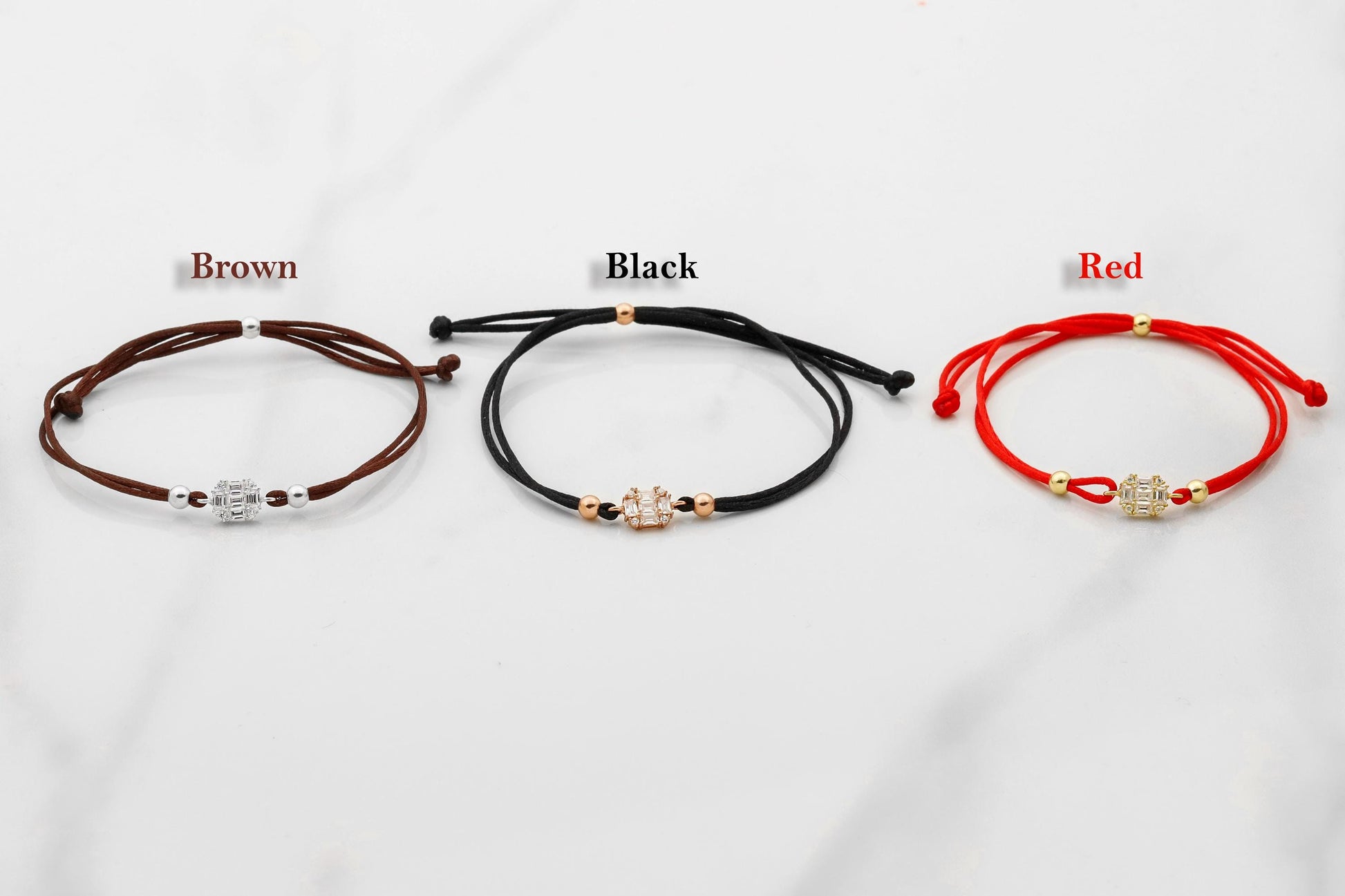 Three bracelets in brown, black, and red on a white background