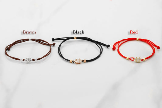 Three bracelets in brown, black, and red on a white background