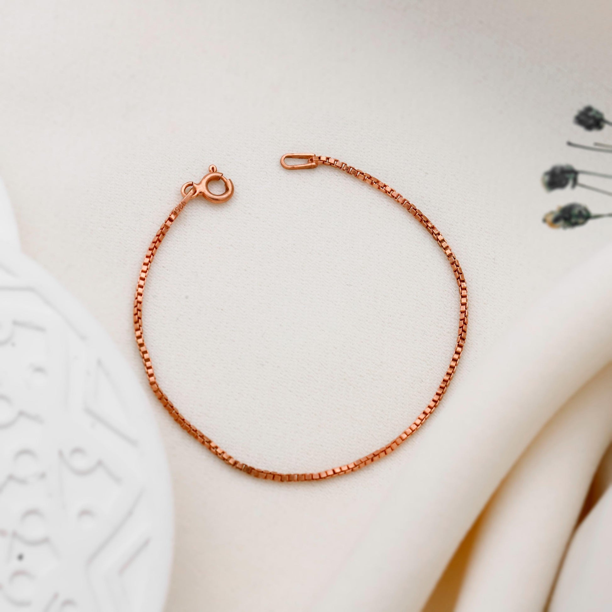 Rose gold chain bracelet on a white surface