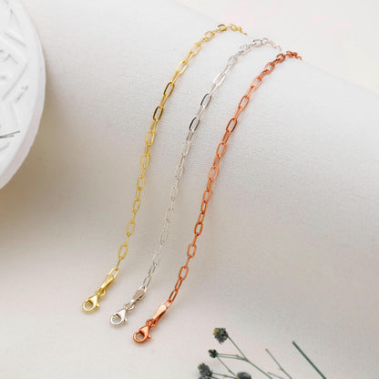 Three gold, silver, and rose gold chain necklaces on a light surface.