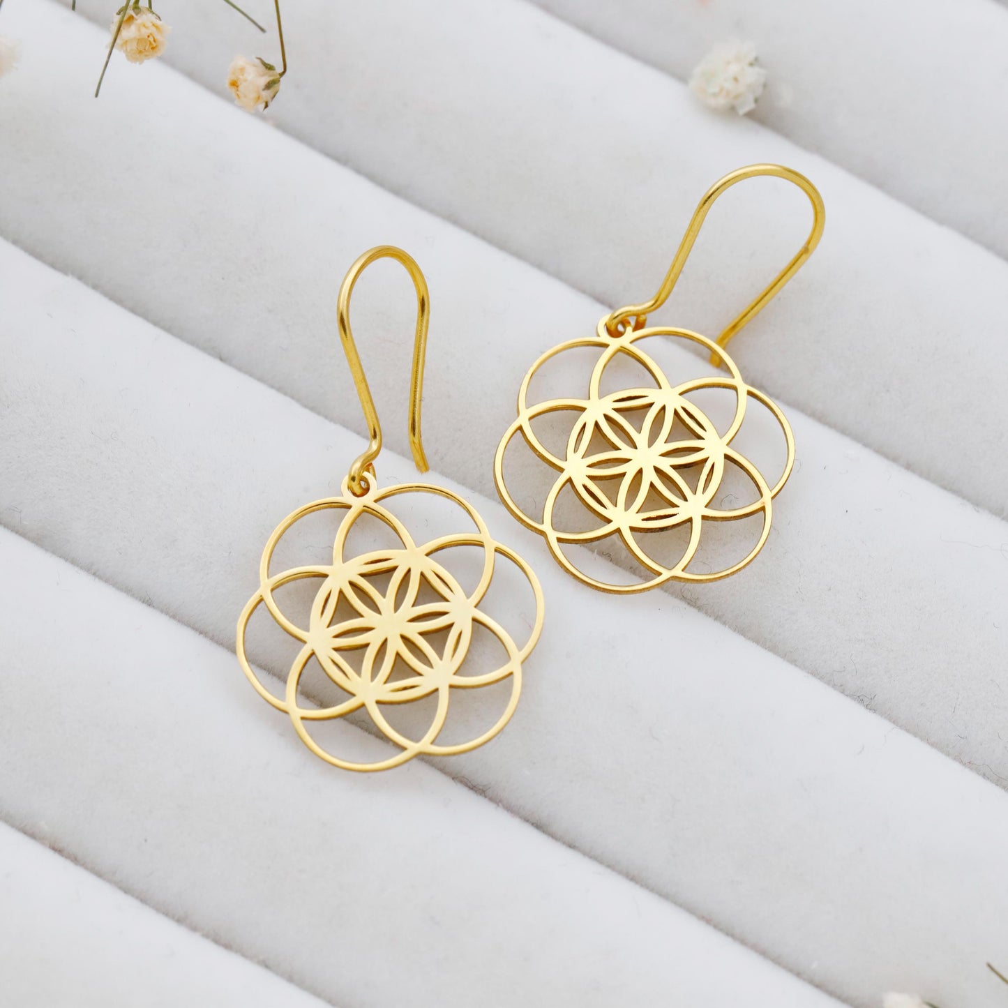 Gold floral earrings on a white fabric background