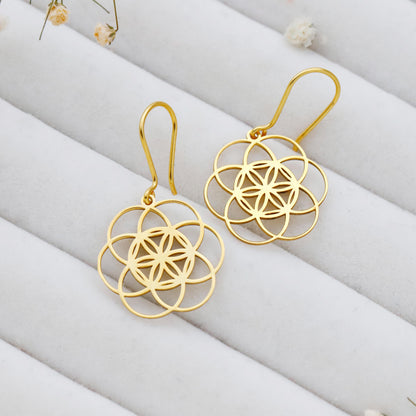 Gold floral earrings on a white fabric background