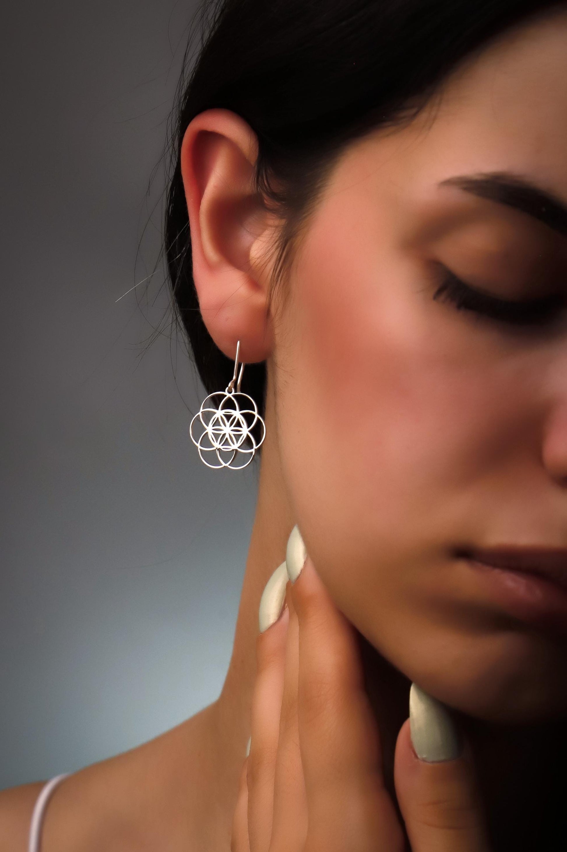Close-up of a woman wearing a geometric earrings with a neutral background