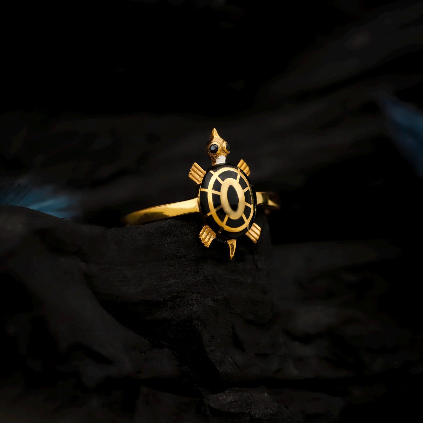 Gold turtle-shaped ring on a dark textured background