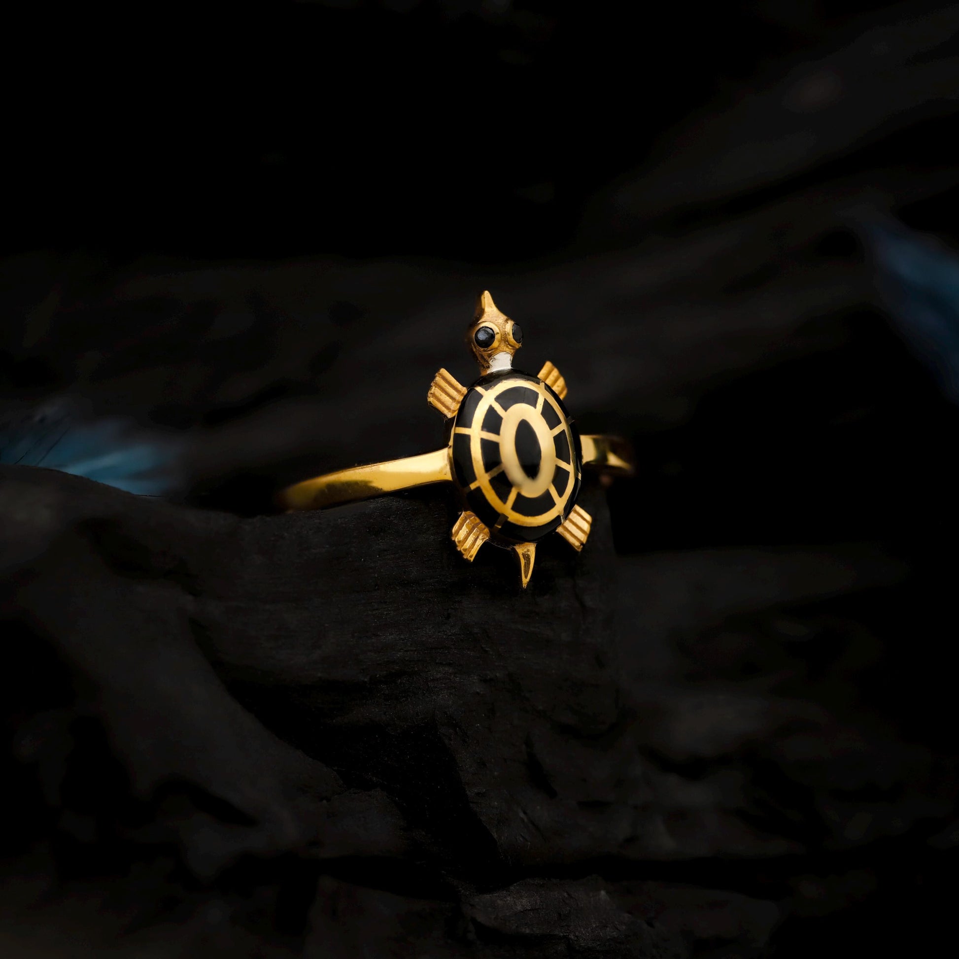 Gold turtle-shaped ring on a dark textured background