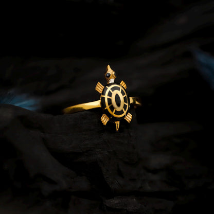 Gold turtle-shaped ring on a dark textured background