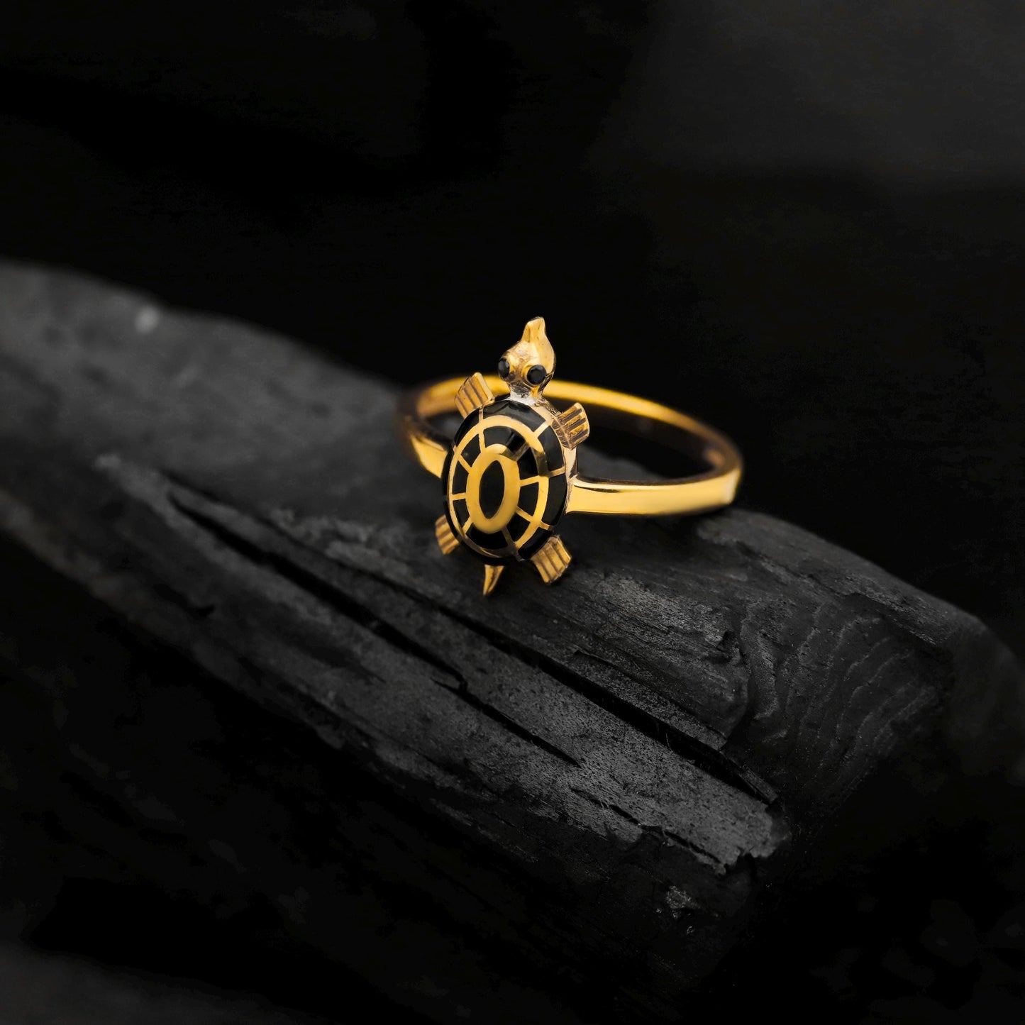 Gold ring with a black center design on a dark surface