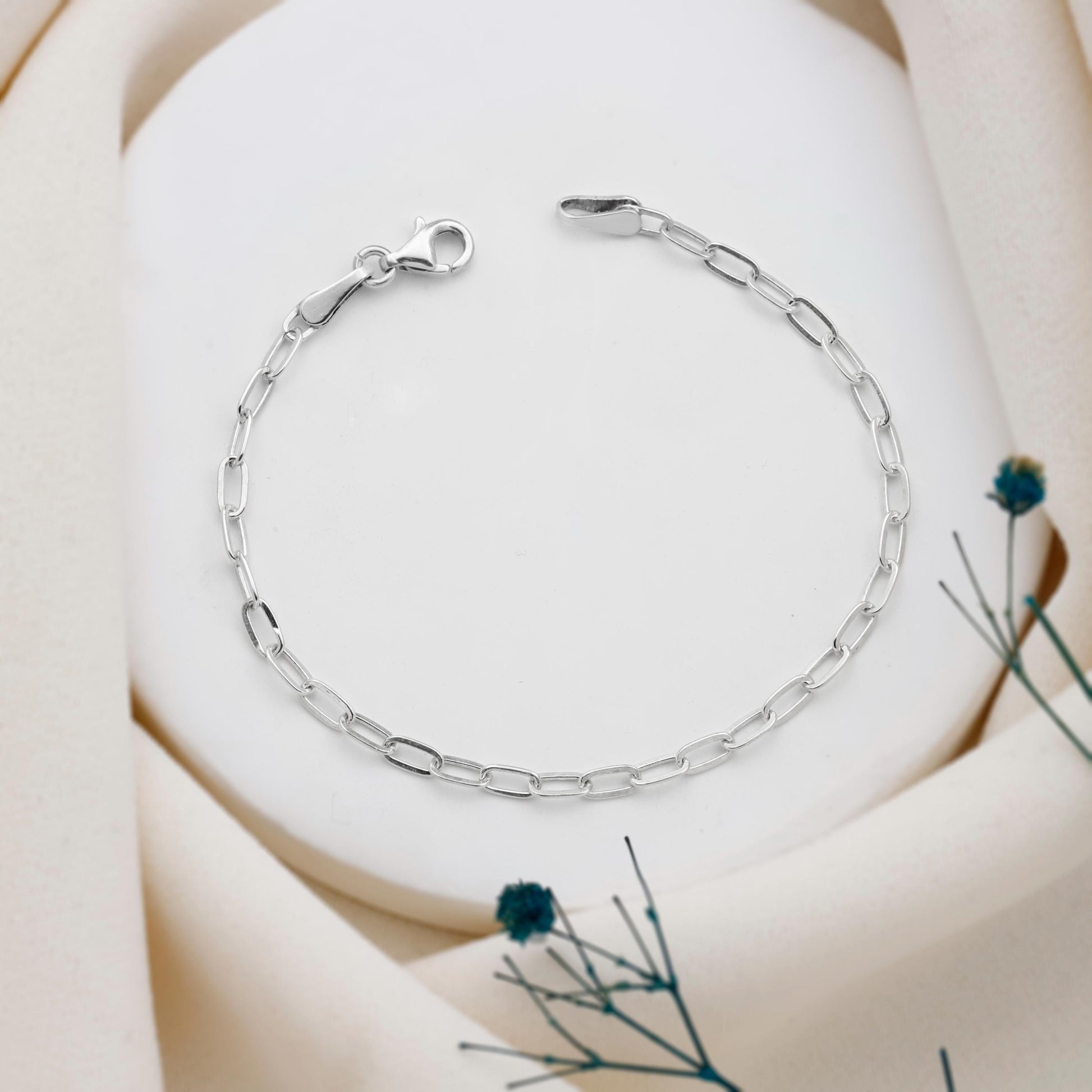 Silver bracelet on a soft beige background with dried flowers