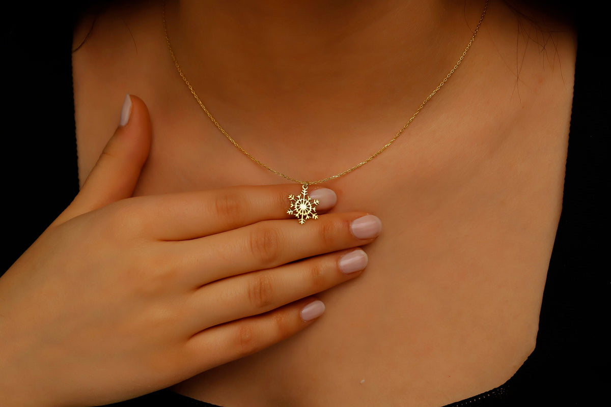 Gold necklace with a turtle pendant worn by a person against a black background