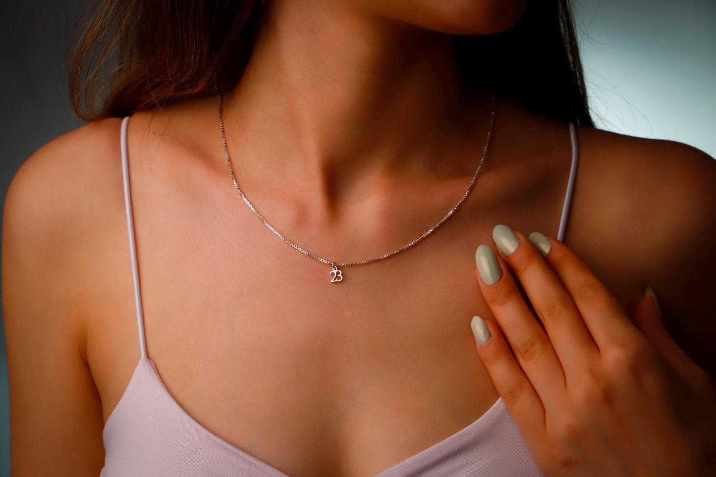Close-up of a woman wearing a silver necklace with a small pendant.