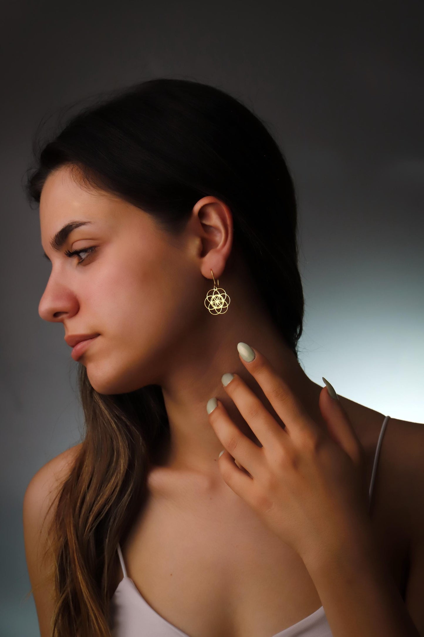 Woman wearing a gold earring against a dark background