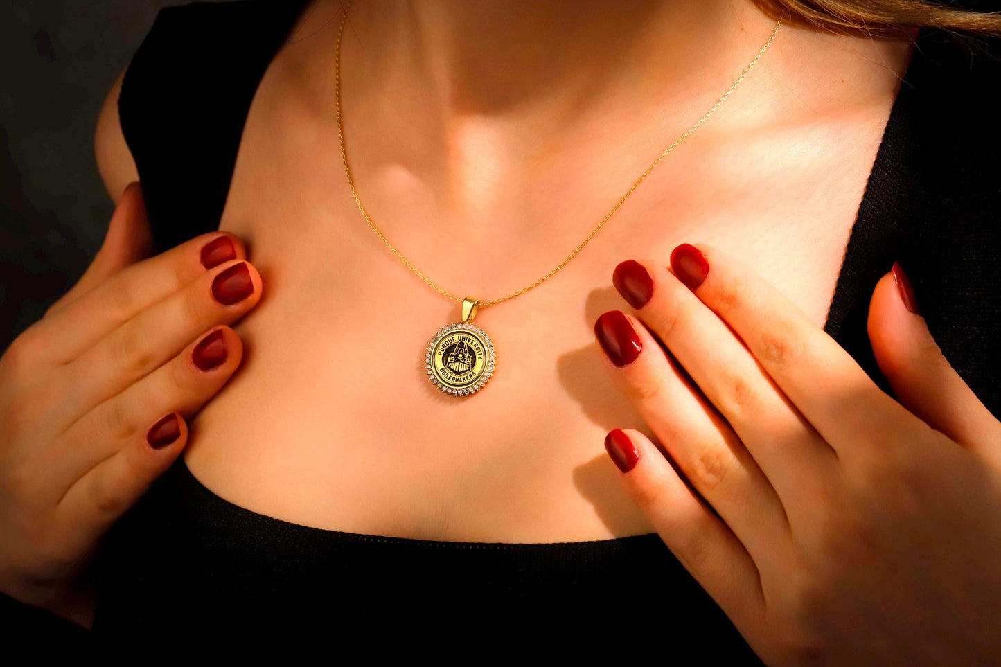 Woman wearing a gold necklace with a pendant, hands touching chest