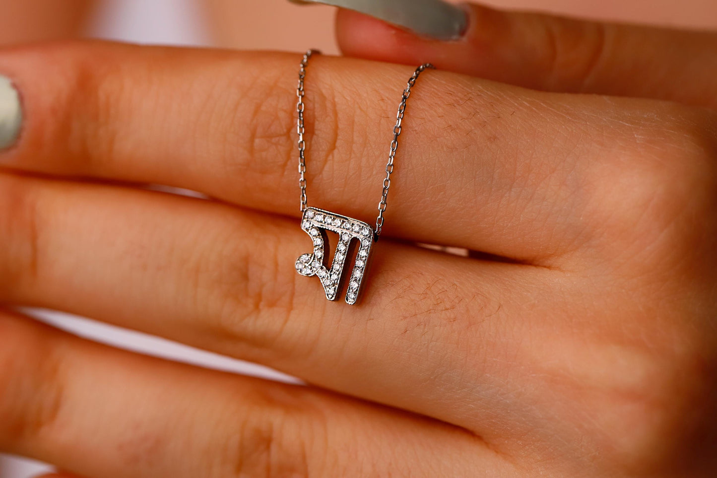 Silver necklace with a diamond pendant on a hand