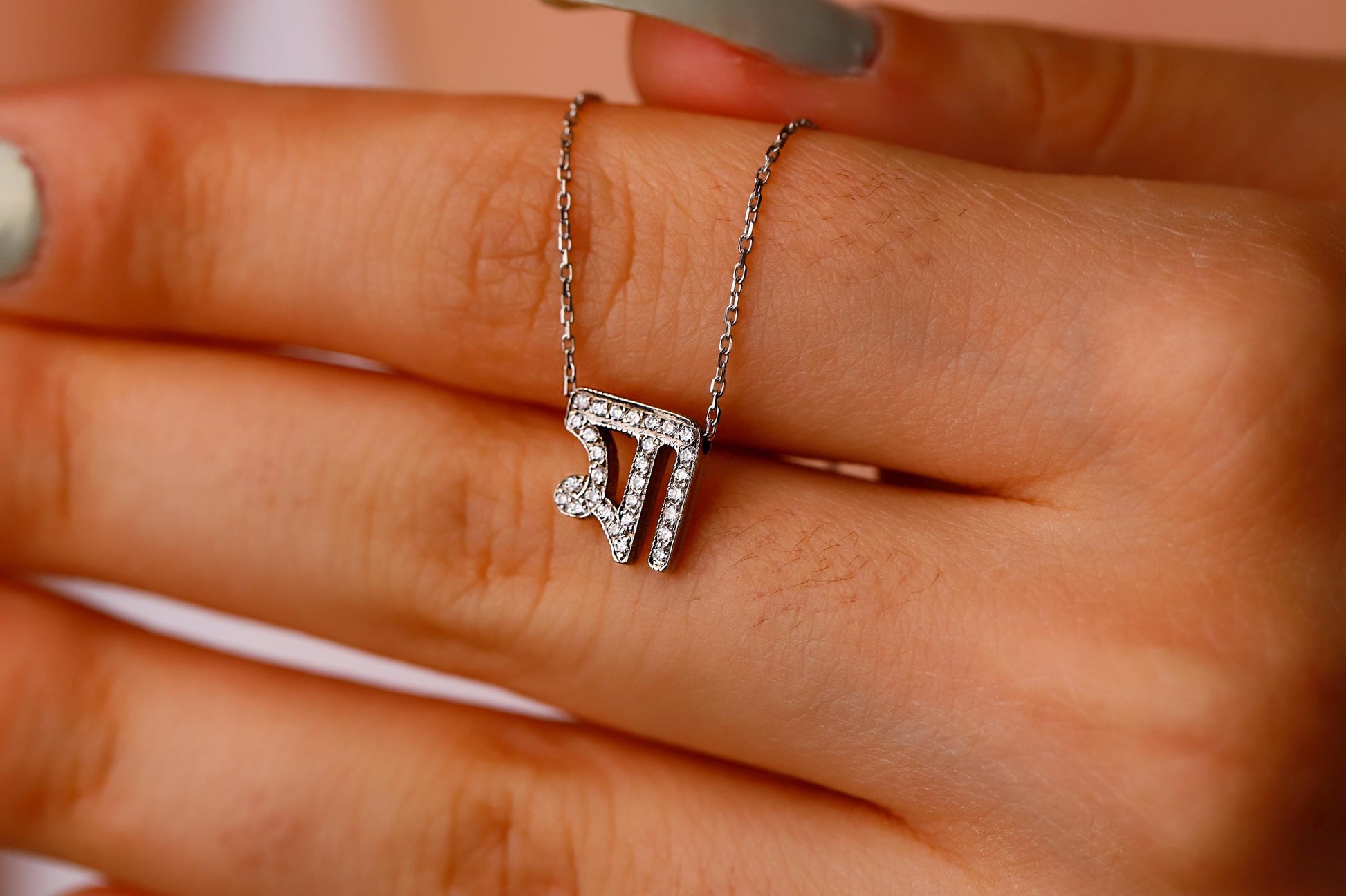 Silver necklace with a diamond pendant on a hand