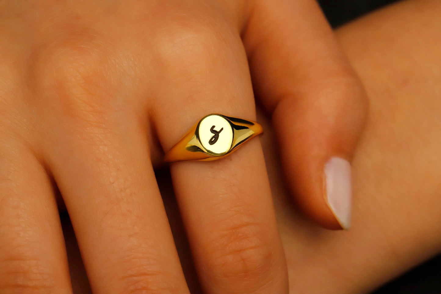 Gold ring with a symbol on a person's finger