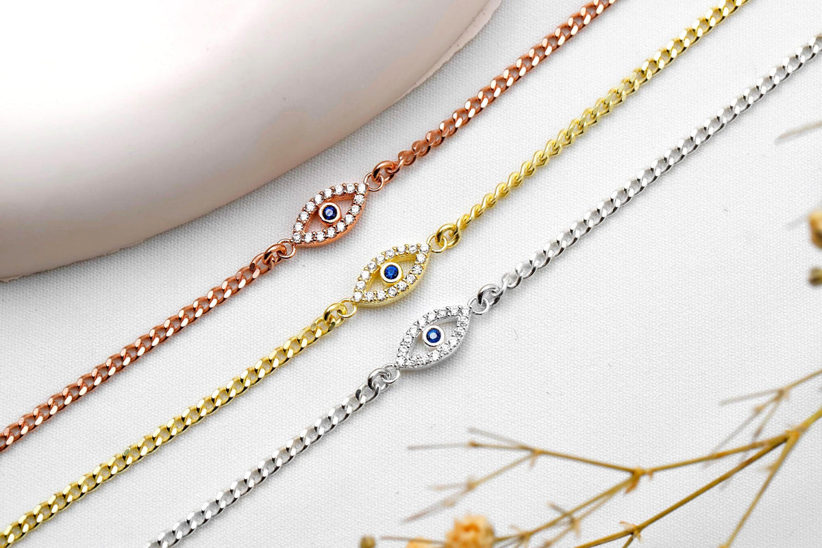 Three gold, rose gold, and silver bracelets with eye designs on a light background.