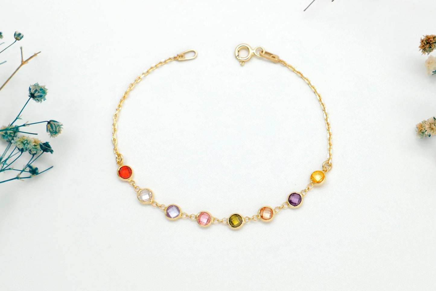 Gold bracelet with colorful beads on a white background