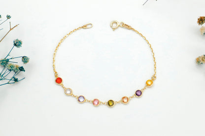 Gold bracelet with colorful beads on a white background