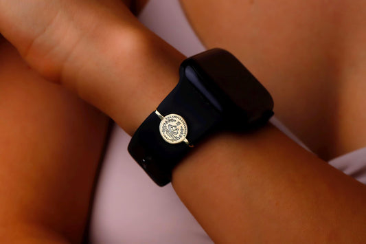Black smartwatch with a gold emblem on a wrist against a neutral background