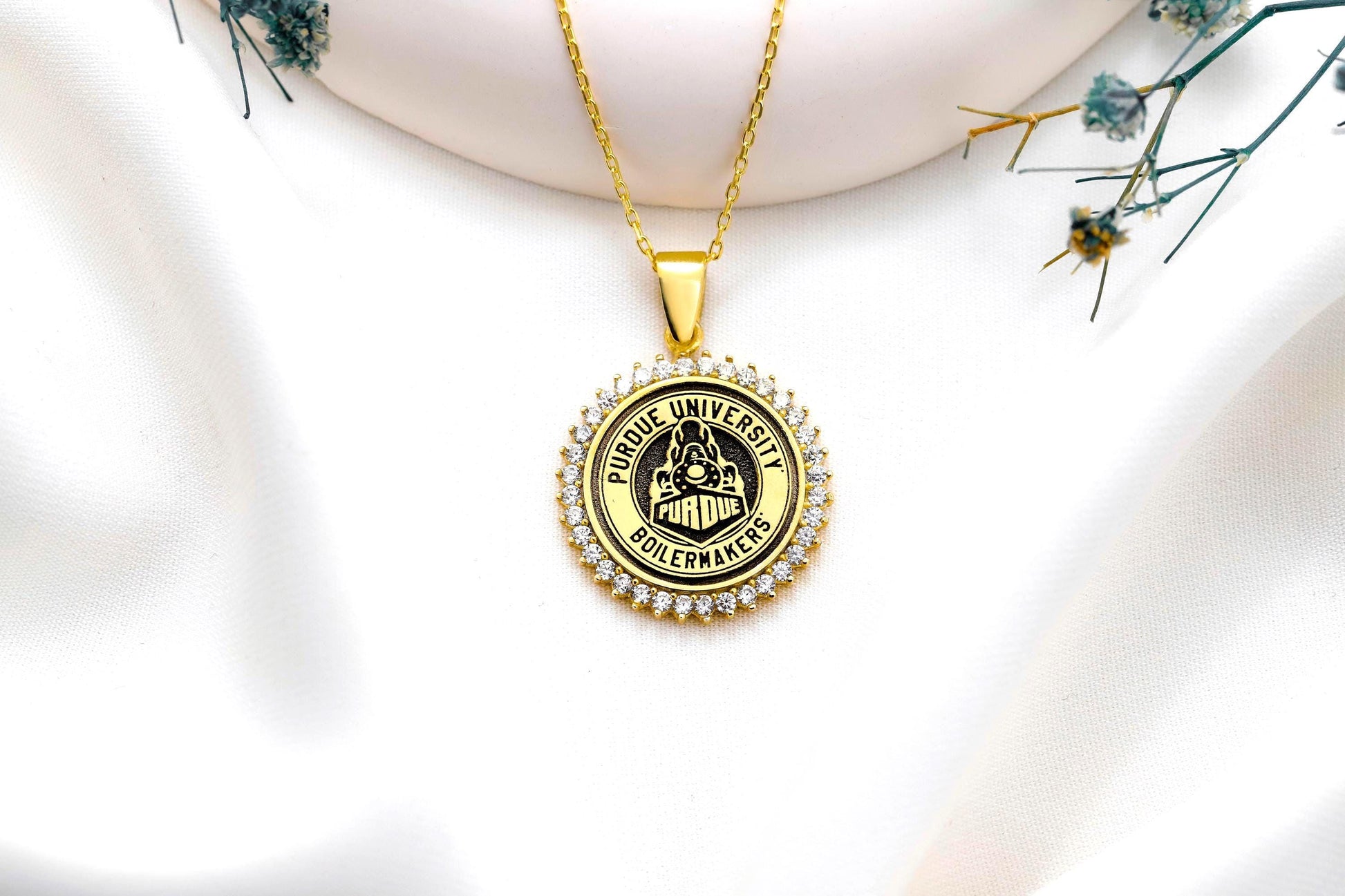 Gold pendant with 'Purdue University Goldenakers' on a white background