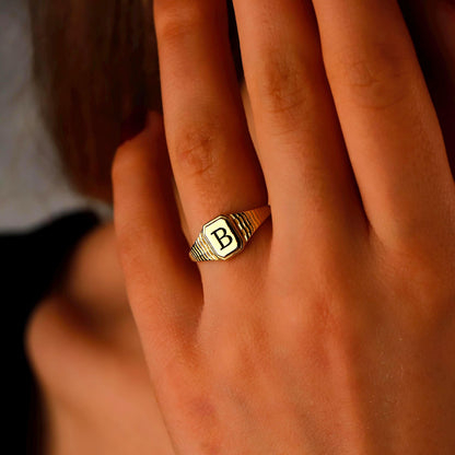 Gold ring with a letter 'B' on a person's finger