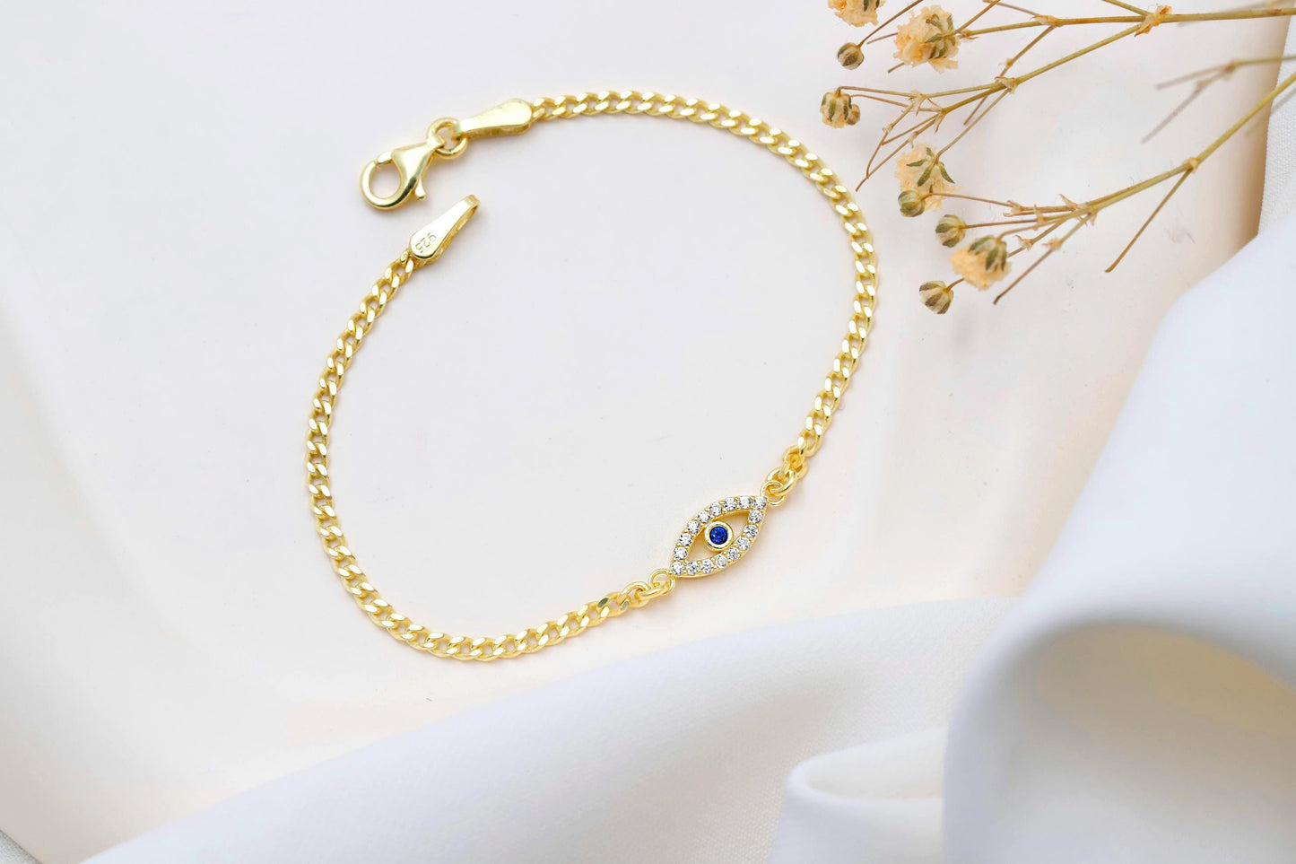 Gold bracelet with a blue gemstone on a light background