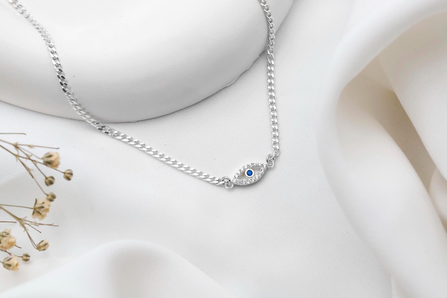 Silver bracelet with a blue gemstone on a white fabric background