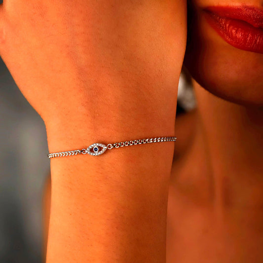 Silver bracelet with an eye design on a person's wrist, with a blurred background.